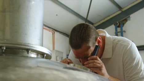 Male-worker-examining-a-distillation-tank-4k
