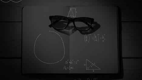 Mathematical-equations-and-figures-and-eyeglass-in-an-open-notebook-