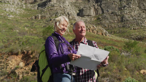 Active-senior-couple-looking-map-on-mountains