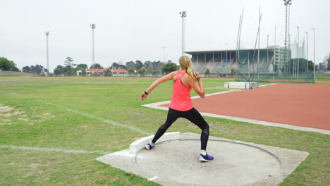 Rear-view-of-Caucasian-female-athlete-practicing-shot-put-throw-at-sports-venue-4k