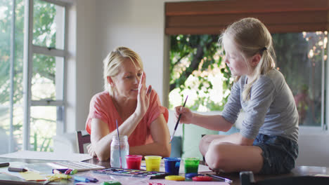 Side-view-of-Caucasian-woman-painting-with-her-daughter-at-home-and-giving-a-high-five