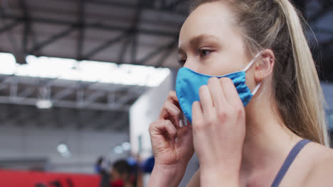 Fit-caucasian-woman-adjusting-her-face-mask-in-the-gym