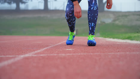 Low-section-of-female-athlete-tying-shoelace-on-a-running-track-at-sports-venue-4k