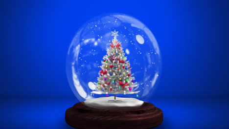 Digitale-Animation-Von-Schnee,-Der-über-Einen-Weihnachtsbaum-In-Einer-Schneekugel-Vor-Blauem-Hintergrund-Fällt