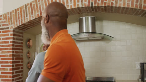 African-american-senior-couple-dancing-together-in-the-kitchen-at-home