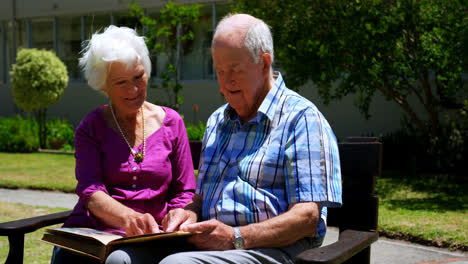 Front-view-of-active-Caucasian-senior-couple-looking-at-photo-album-in-the-garden-of-nursing-home-4k