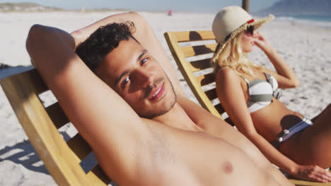 Caucasian-couple-sitting-on-sunbeds-on-the-beach