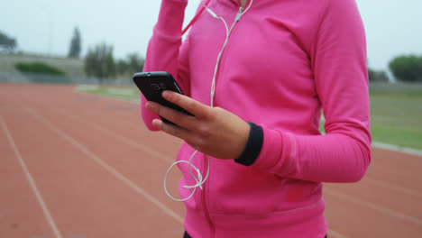 Mid-section-of-female-athlete-listening-music-on-mobile-phone-at-sports-venue-4k