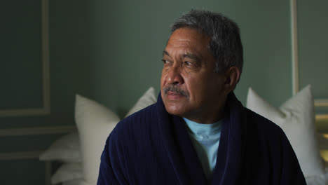 Senior-mixed-race-man-sitting-up-in-bed-looking-away