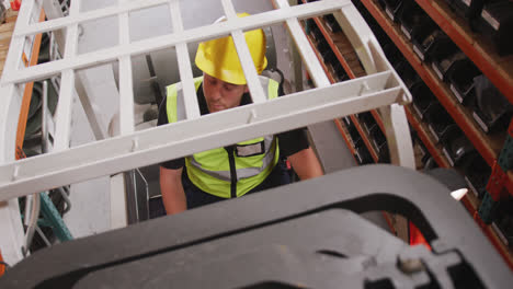 Caucasian-male-factory-worker-at-a-factory-with-a-hat-and-high-vis-vest,-using-a-truck
