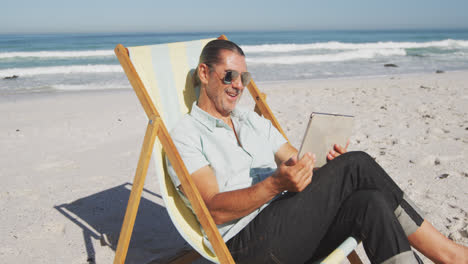 Senior-Caucasian-man-sitting-on-sunbeds-at-the-beach.