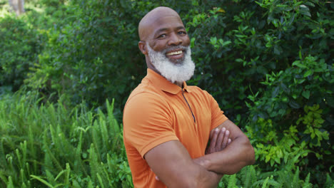Portrait-of-african-american-senior-man-smiling-and-crossing-his-arms-in-the-garden