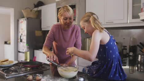 Side-view-of-Caucasian-woman-cooking-with-her-daughter-at-home