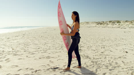 Female-surfer-putting-the-surfboard-in-sand-4K-4k