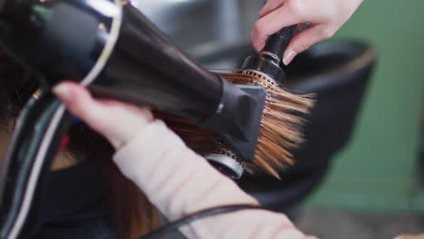 Female-hairdresser-blow-drying-hair-of-female-customer-at-hair-salon