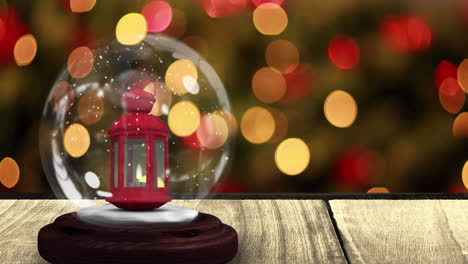 Digital-animation-of-snow-falling-over-christmas-lantern-in-snow-globe-on-wooden-surface