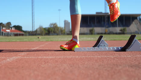 Low-section-of-female-athlete-taking-starting-position-on-a-running-track-at-sports-venue-4k