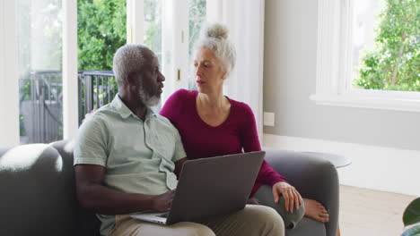 Mixed-race-senior-couple-using-laptop-in-the-living-room-at-home