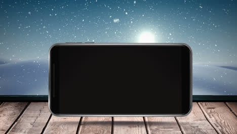 Digital-animation-of-smartphone-on-wooden-surface-against-snow-falling-on-winter-landscape