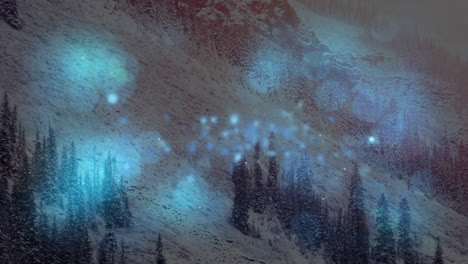 Digitale-Komposition-Aus-Blau-Leuchtenden-Lichtpunkten-Vor-Einer-Schneelandschaft-Mit-Bergen-Und-Bäumen