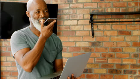 Älterer-Mann,-Der-Mit-Dem-Mobiltelefon-Telefoniert,-Während-Er-Einen-Laptop-4K-Benutzt