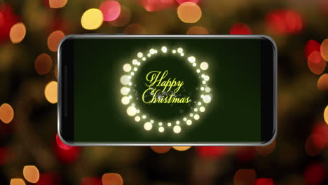 Animation-of-happy-christmas-text-with-fairy-lights-on-smartphone-screen-with-out-of-focus-light