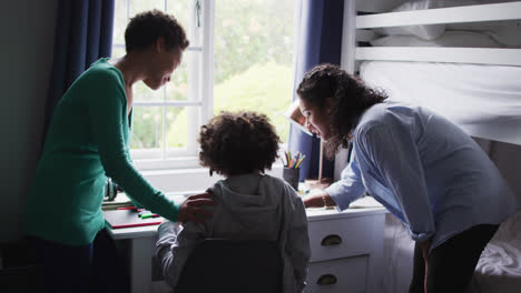 Mixed-race-lesbian-couple-helping-daughter-working-at-a-desk
