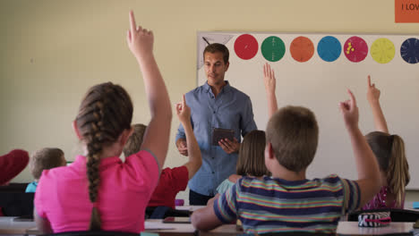 Group-of-kids-raising-their-hands-in-the-class