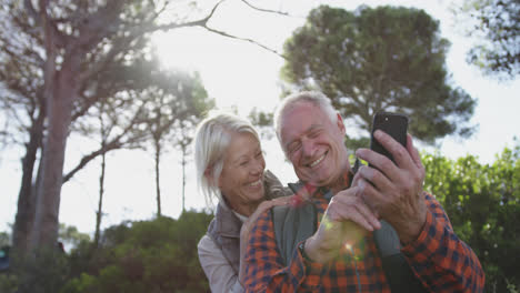 Happy-senior-couple-holding-smartphone-in-forest