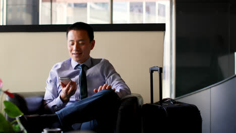 Front-view-of-asian-businessman-talking-on-mobile-phone-in-hotel-lobby-4k
