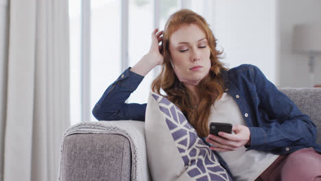 Frau-Benutzt-Smartphone,-Während-Sie-Zu-Hause-Auf-Der-Couch-Sitzt
