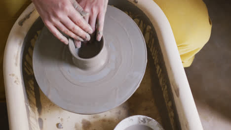 Close-up-view-of-female-potter-creating-pottery-on-potters-wheel-at-pottery-studio
