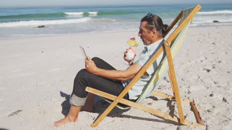 Senior-Caucasian-man-sitting-on-sunbeds-at-the-beach.