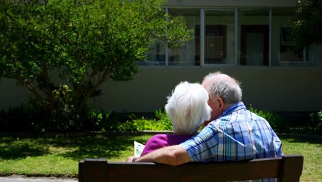 Rear-view-of-active-Caucasian-senior-couple-looking-at-photo-album-in-the-garden-of-nursing-home-4k