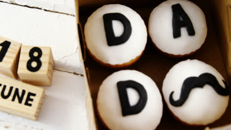 Cupcakes-with-text-dad-in-a-box-on-wooden-plank-4k