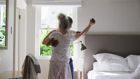 Älteres-Paar-Gemischter-Abstammung-Tanzt-Zusammen-Im-Schlafzimmer-Zu-Hause