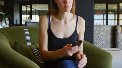 Front-view-of-young-caucasian-businesswoman-texting-and-talking-on-mobile-phone-in-modern-office-4k