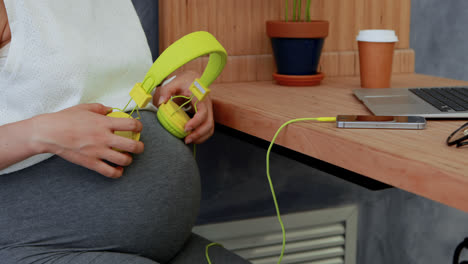 Pregnant-woman-placing-headphones-on-her-belly-4k
