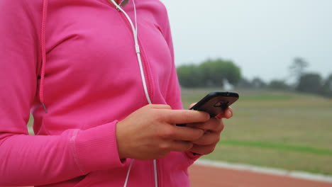 Mid-section-of-female-athlete-using-mobile-phone-at-sports-venue-4k