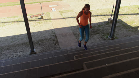 Front-view-of-Caucasian-female-athlete-exercising-on-steps-at-sports-venue-4k