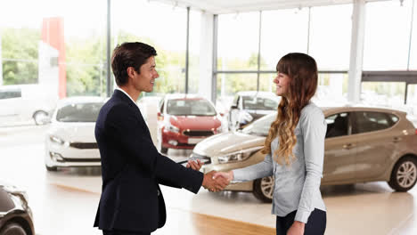 Caucasian-male-and-female-shaking-hands-in-a-car-distributor
