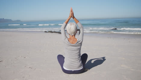 Mujer-Caucásica-Mayor-Practicando-Yoga-En-La-Playa
