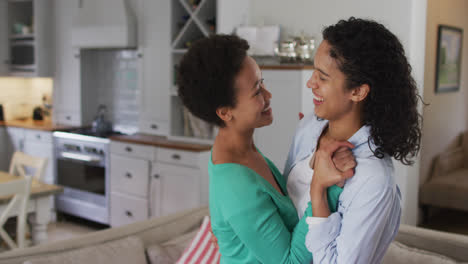 Romantic-mixed-race-lesbian-couple-dancing-in-sitting-room