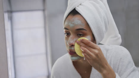 Mixed-race-woman-removing-face-mask-in-bathroom