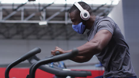 African-american-man-wearing-face-mask-exercising-at-gym