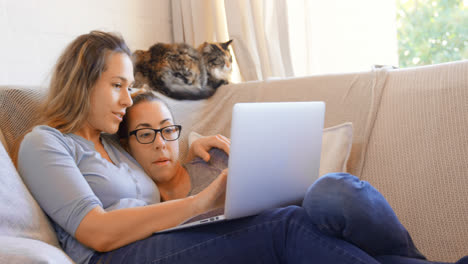 Lesbian-couple-using-laptop-in-living-room-4k