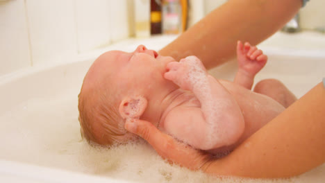 Mother-giving-her-baby-boy-a-bath-in-bathroom-4k