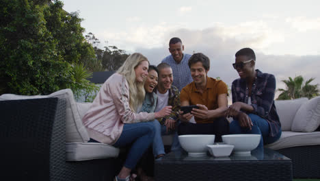 Group-of-friends-using-a-smartphone-and-discussing-on-a-rooftop