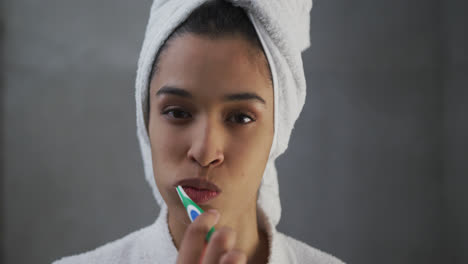 Portrait-of-mixed-race-woman-brushing-her-teeth-in-bathroom