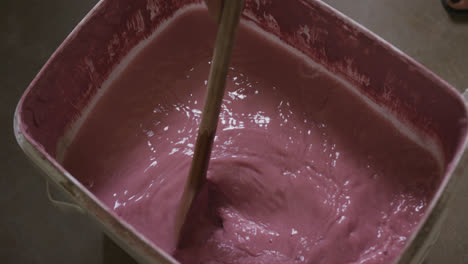 Close-up-view-of-potter-mixing-paint-in-a-container-at-pottery-studio
